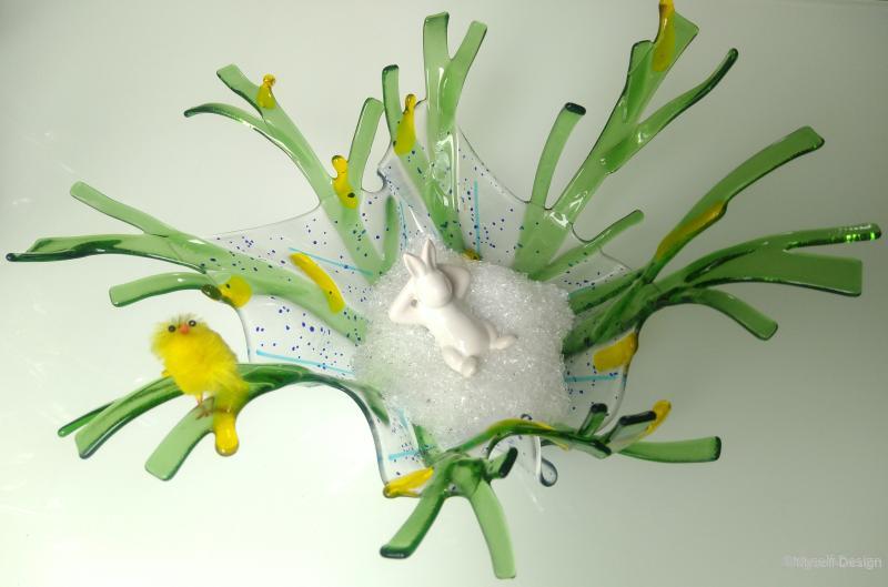 Osterhase liegt in Glasbett in grün-gelber geschwungener Schale
