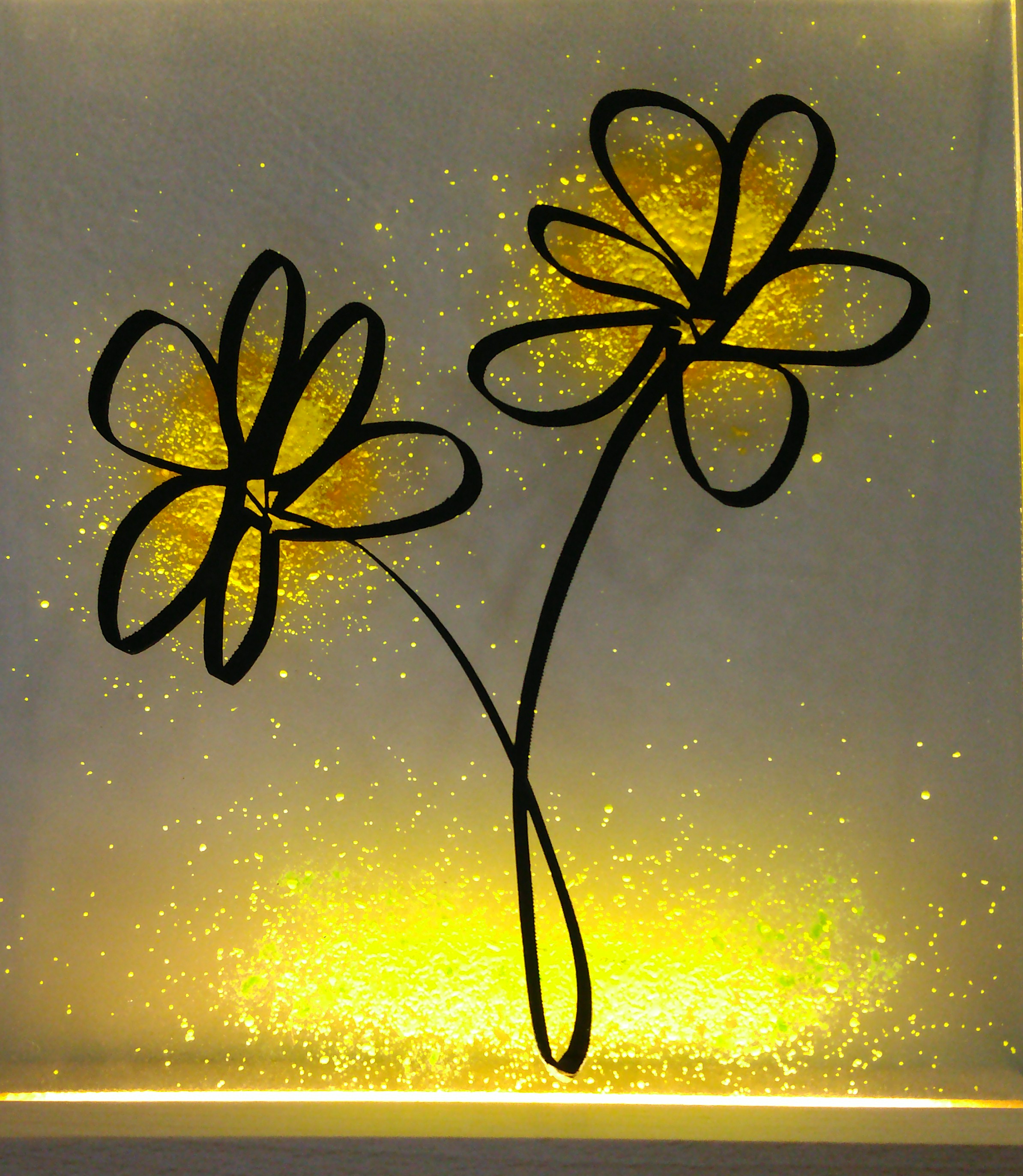 Eine beleuchtete, rechteckige Glasplatte mit Blumenmotiv